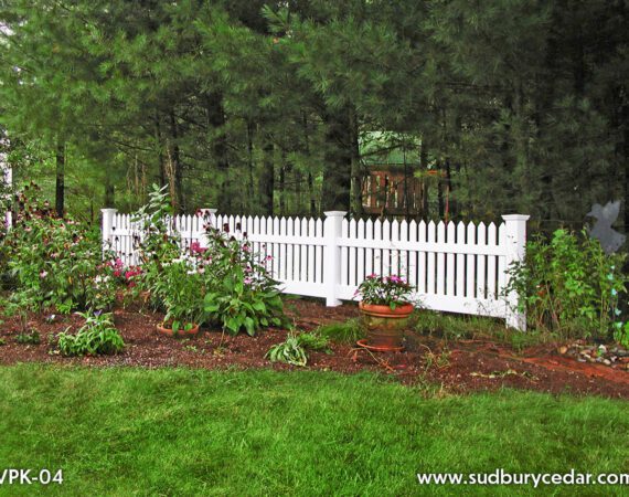 Decorative white vinyl picket fence installed alongside landscaped garden bed and residential walkway in Sudbury, Massachusetts.