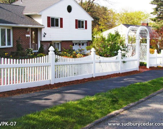 Decorative white vinyl arbor with curved vinyl picket fencing installed in landscaped Massachusetts residential yard.