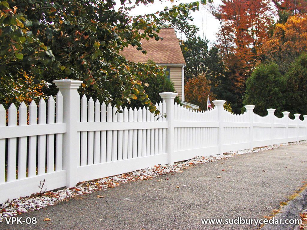Curved white vinyl scalloped picket fence installed along landscaped residential property in Massachusetts.