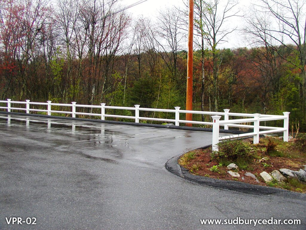 White vinyl post and rail fence installed along curved residential driveway and landscaped property in Massachusetts.