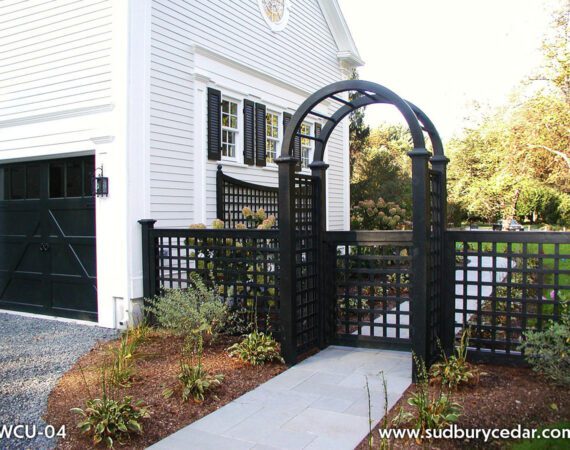 Black lattice fence with double arched gate complements the white colonial home with black shutters and trim. Sudbury MA