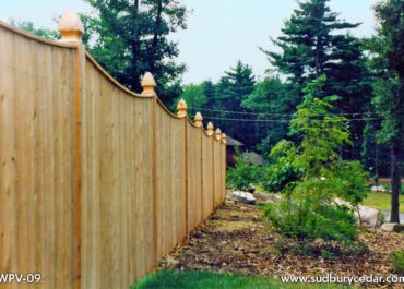 Scalloped cedar privacy fence with vertical boards and landscaped surroundings in Acton, MA