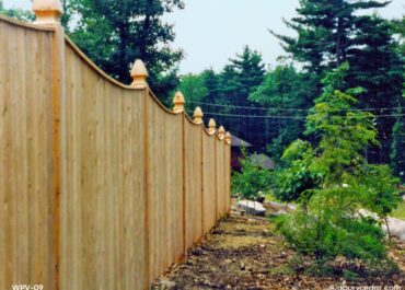 Scalloped cedar privacy fence with vertical boards and landscaped surroundings in Acton, MA