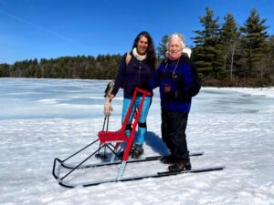 All Out Adventures program leaders standing with adaptive kicksled on frozen lake