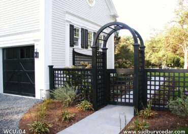 : Black lattice fence with double arched gate complements the white colonial home with black shutters and trim.