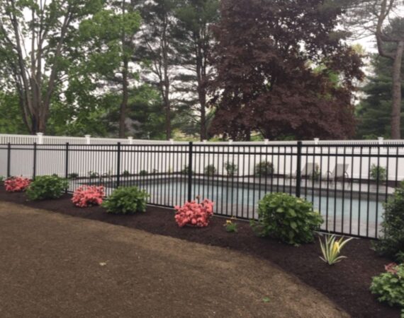 Black aluminum pool fence installed around backyard swimming pool with landscaping in Sudbury MA
