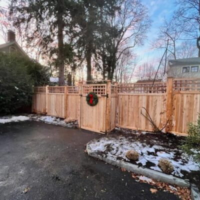 Northern white cedar privacy fence with lattice top and gate in snowy winter landscape Concord Massachusetts showcasing durability in New England weather
