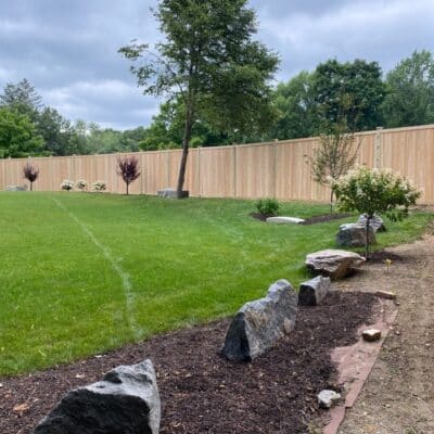 Northern white cedar privacy fence enclosing residential backyard with landscaping in Bolton Massachusetts