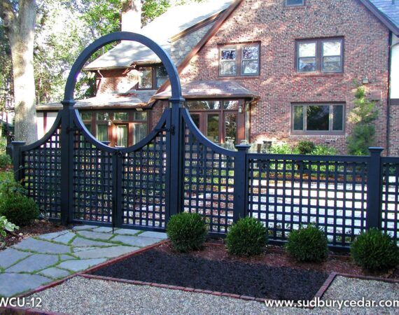 Black lattice fence with an arched gate in front of a brick home, showcasing an elegant fence design that complements the home’s architecture MetroWest Massachusetts