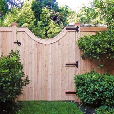 Northern white cedar fence with custom curved top gate and black hardware in Sudbury Massachusetts demonstrating natural rot and insect resistance