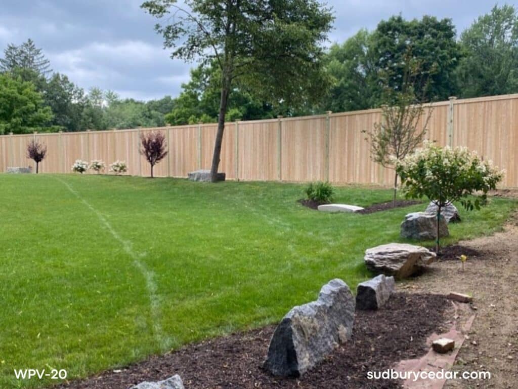 Cedar privacy fence enclosing backyard in Bolton MA with landscaped lawn and trees