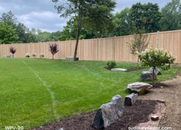 Cedar privacy fence enclosing backyard in Bolton MA with landscaped lawn and trees