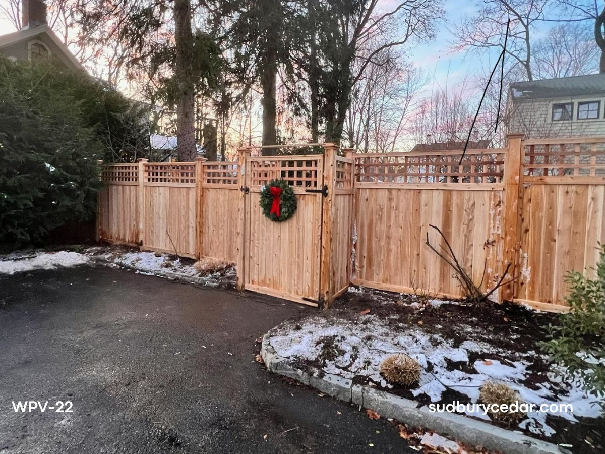 Decorative cedar privacy fence with square lattice top and custom double gates installed along a driveway in Concord, MA