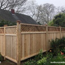 Cedar privacy fence with lattice top and wood posts in landscaped yard in Stow, MA.