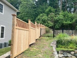Cedar privacy fence following slope with lattice top and transition to metal fence in Wayland, MA