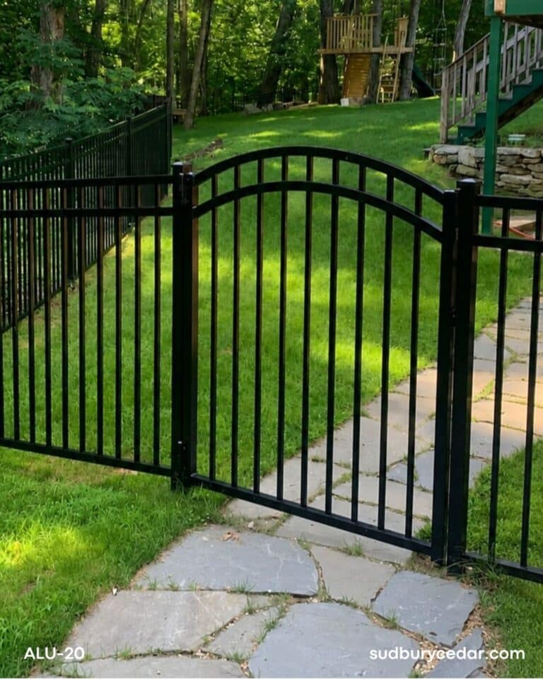 Decorative black aluminum fence with arched gate and ornamental finials surrounding a landscaped residential property