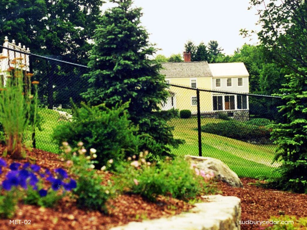 Black vinyl-coated chain link fence surrounding a large landscaped residential property in Massachusetts