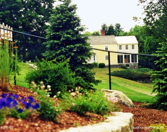 Black vinyl-coated chain link fence surrounding a large landscaped residential property in Massachusetts