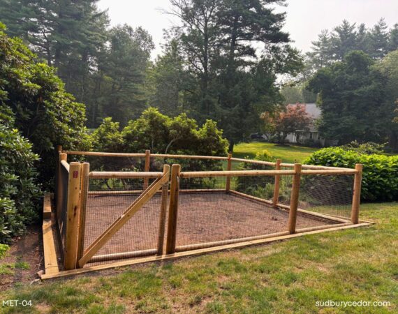 Cedar post and wire garden enclosure with custom gate in a landscaped Massachusetts backyard