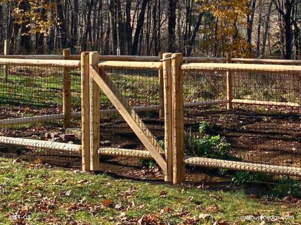 Cedar post and wire garden fence with gate surrounding a raised vegetable garden in a wooded Massachusetts backyard