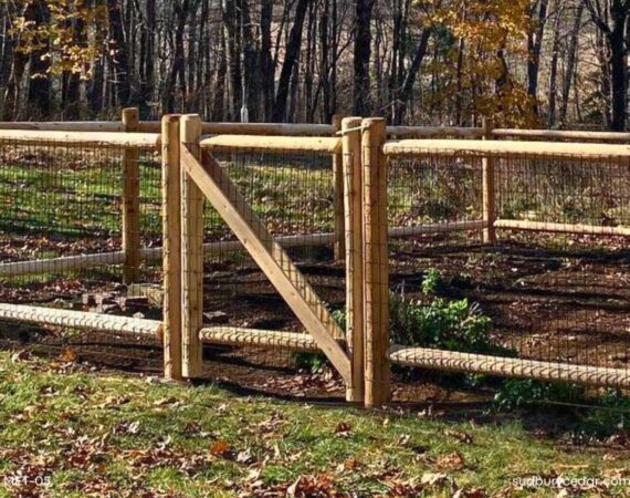 Cedar post and wire garden fence with gate surrounding a raised vegetable garden in a wooded Massachusetts backyard