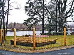 Welded wire fence with cedar posts surrounding a raised garden bed near a waterfront property in Wayland, Massachusetts