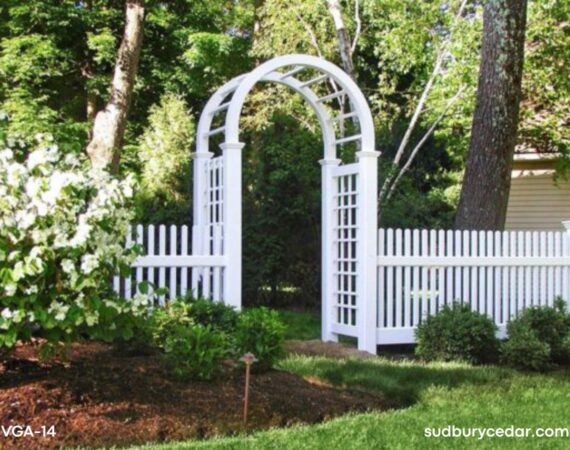 Decorative white vinyl arbor with lattice side panels and matching vinyl picket fencing installed in landscaped Weston, Massachusetts backyard.