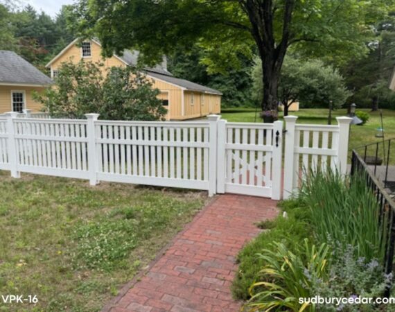 White vinyl picket fence installed along residential walkway with landscaped front yard and garden entrance in Sudbury, Massachusetts.