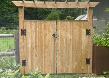 Custom cedar garden gate with pergola-style arbor and black decorative hardware installed in MetroWest Massachusetts