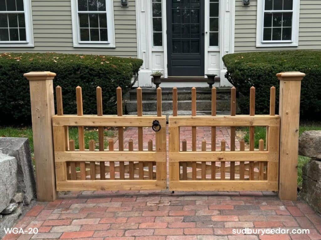 Custom cedar entry gate with decorative picket detailing and oversized cedar posts installed at a brick walkway in Concord MA