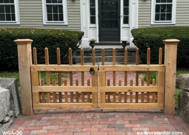 Custom cedar entry gate with decorative picket detailing and oversized cedar posts installed at a brick walkway in Concord MA