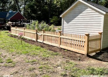 decorative cedar picket fence enclosing backyard garden area in massachusetts