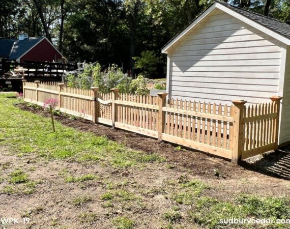 decorative cedar picket fence enclosing backyard garden area in massachusetts
