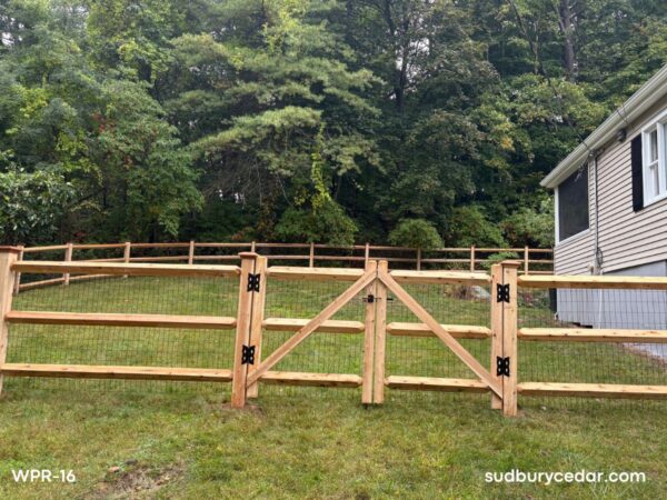 Cedar post and rail dog fence with black wire mesh and matching walk gate installed in a backyard in Sudbury, Massachusetts, providing a secure enclosure while preserving open views.
