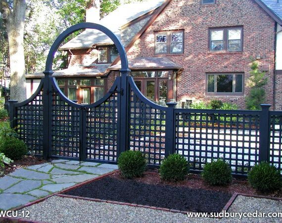 attice fence with an arched gate in front of a brick home, showcasing an elegant fence design that complements the home’s architecture.
