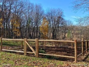 Cedar post and wire garden fence with gate surrounding a raised vegetable garden in Lincoln, Massachusetts backyard