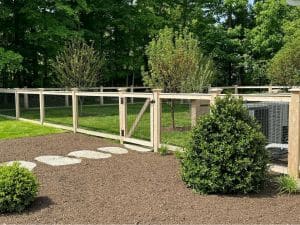 Cedar post and wire fence with matching gate enclosing a landscaped backyard in Concord, Massachusetts