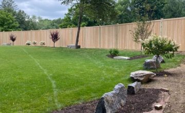 Cedar privacy fence enclosing backyard in Bolton MA with landscaped lawn and trees
