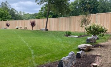 Cedar privacy fence enclosing backyard in Bolton MA with landscaped lawn and trees